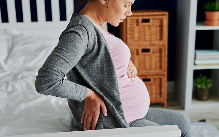 pregnant woman holding her lower back